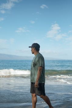 a man is walking along the beach with his surfboard in hand and water behind him