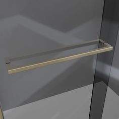 a glass shower door with a gold handle on the bottom and an empty shelf above it