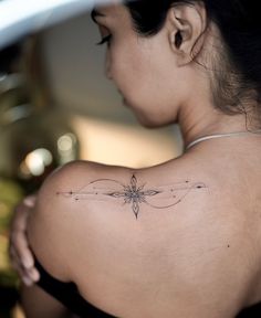 a woman with a dragonfly tattoo on her upper arm and shoulder, looking down at the ground