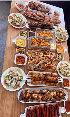 a wooden table topped with lots of different types of foods and condiments on it