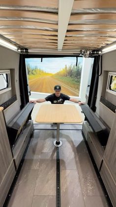 a man sitting at a table in the back of a truck with its doors open