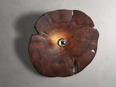 a wooden object with holes in it on a gray wall and a light fixture hanging from the side