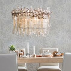 a chandelier hanging from the ceiling over a dining room table with white chairs