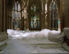 an old church with snow piled on the floor and stained glass windows in the background