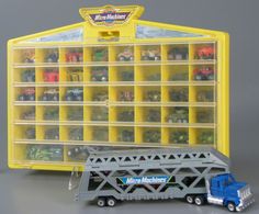 a toy truck is parked in front of a large plastic storage case with cars on it