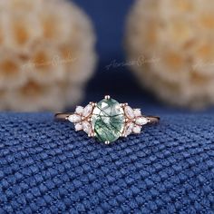 a green ring sitting on top of a blue cloth next to a white flower arrangement