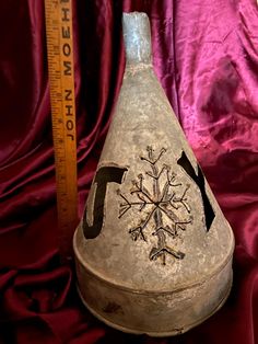 an old hat with a snowflake on it next to a measuring tape and red fabric