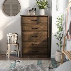 a bedroom scene with focus on the chest of drawers and plants in the window sill