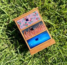 a small wooden box sitting on top of green grass next to a blue hole in the ground