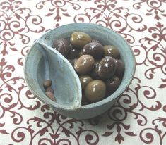 a bowl filled with olives sitting on top of a table