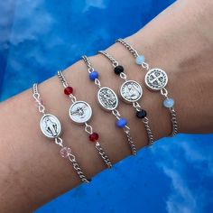 a woman's arm with four different bracelets on it, including an image of jesus