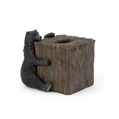 a black bear sitting on top of a tree stump next to a toilet paper dispenser