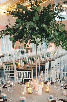 an elegant centerpiece with candles and greenery is displayed on the tables at this wedding reception