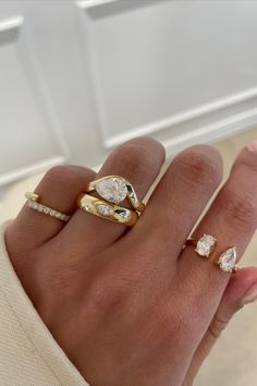 a woman's hand with three gold rings on it and two diamonds in the middle