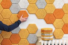 a person is touching the wall with his hand next to some yellow and gray hexagonal tiles