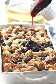 blueberry bread pudding being drizzled with red liquid from a bottle in a white dish