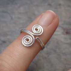 a person's finger with a ring on it that has two spirals in the middle