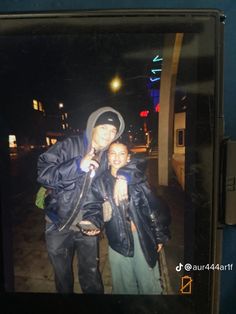 a man and woman standing next to each other in front of a building at night