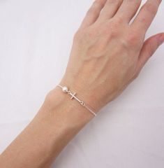 SOLID STERLING SILVER PARTS - A QUALITY BRACELETThis lovingly hand-made bracelet is crafted using a solid sterling silver cross that measures just under 3/4 inch long. A 6mm Swarovski pearl comes in your choice of 5 colors. The sturdy sterling silver chain and lobster clasp make this a durable bracelet. Comes in a gift box.SIZING - IMPORTANT: To determine bracelet size, measure snugly around your wrist and add 1/2 inch to get your bracelet size. Do NOT order in your exact wrist measurement. Minimalist Sterling Silver Cross Bracelet, Elegant Sterling Silver Cross Rosary Bracelet, Adjustable Silver Pearl Bracelet For Baptism, Silver Cross Bracelet With Adjustable Chain, Mothers Birthstone Bracelet, Nickel-free Silver Cross Bracelets, Tiny Cross, Moms Bracelet, Cross Bracelet