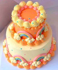 a three tiered cake with colorful icing and rainbow decorations on the top layer