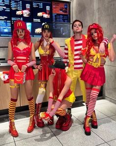 four people dressed in costumes standing next to each other at a fast food restaurant counter