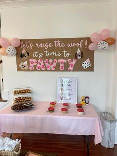 a pink table topped with lots of cupcakes and cake next to a sign that says let's raise the work it's time to party