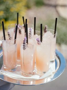 there are many glasses on the tray with drinks in them and some lavender sprigs