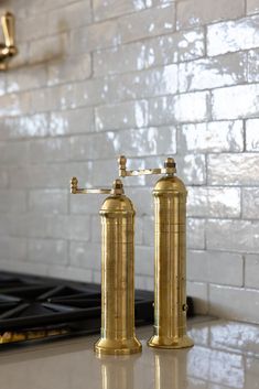 two brass faucets sitting on top of a kitchen counter