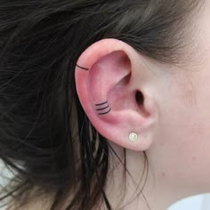 a woman with black lines on her ear and behind the ear is a small white ball