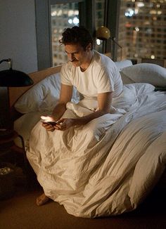 a man sitting in bed looking at his cell phone