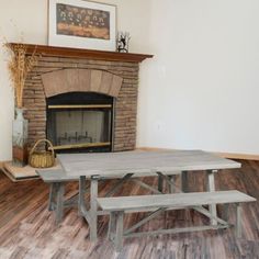 a table and bench in front of a fireplace