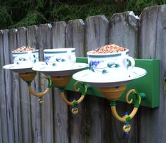 three bird feeders are hanging on the side of a fence