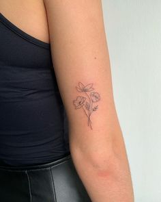 a woman's arm with a small flower tattoo on the left side of her arm