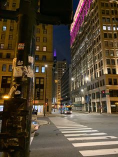 a city street at night with tall buildings in the background