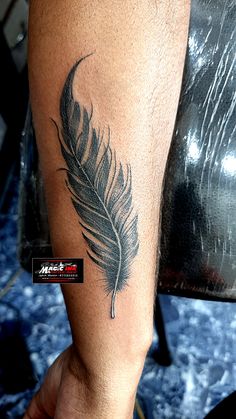 a man's arm with a tattoo on it and a feather in the middle