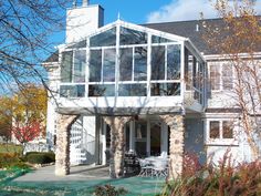 a white house with a large glass window on it's front porch and patio