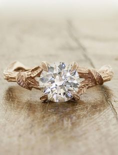 a close up of a ring with a diamond in it on a wooden table top