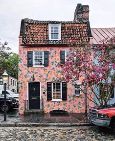 a red truck parked in front of a pink house with flowers painted on it's side