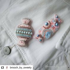 two beaded brooches sitting on top of a white shirt next to each other