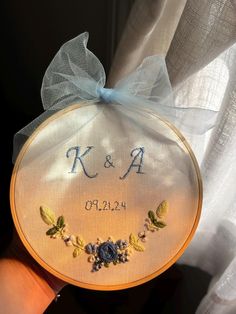 a hand holding a small embroidered item with the word k and p on it's side