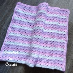 a pink and white crocheted blanket sitting on top of a wooden floor next to a