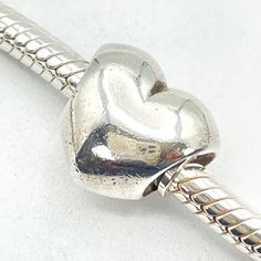 "Authentic PANDORA Sterling Silver Heart Charm, 925 ALE, Retired. Say \"I love you\" with this simple but elegant heart. It matches any bracelet design and reminds her of you. This item is retired from production and may be difficult to find. Charm is pre-owned and in great condition. This beautiful bead will add a special touch to your bracelet creation. The charm shown in the pictures is the one you will receive. Feel free to message me with any questions. Fast shipping and handling from Birmi Classic Gold Heart Bracelet, Classic Sterling Silver Heart Bracelet For Valentine's Day, Classic White Gold Heart Bracelet, Silver Heart Bracelet With Sterling Silver Clasp, Classic Gold Heart Charm Bracelet, Double Heart Bracelet With Heart Beads For Anniversary, Double Heart Beads Bracelet For Anniversary, Anniversary Double Heart Bracelet With Heart Beads, Valentine's Day Heart Bracelet With Sterling Silver Clasp