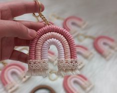 a hand holding a pink and white keychain with a rainbow design on it