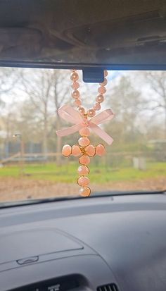 a pink necklace hanging from the dashboard of a car