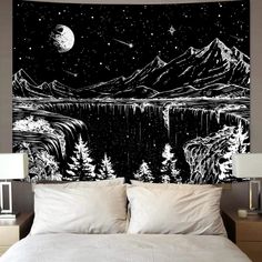 a black and white wall hanging on the side of a bed next to a night sky