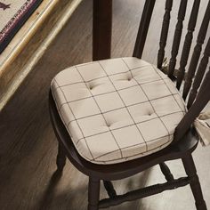 a chair with a seat cushion on it in front of a rug and wooden floor