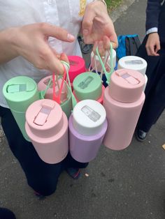 a person is holding several cups and stringing them to each other's handles