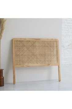 the headboard is made out of wicker and has a plant in front of it