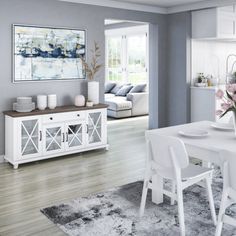 a white dining room table and chairs in front of a couch with flowers on it