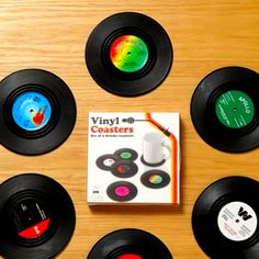 six different colored vinyl records sitting on top of a wooden table next to each other